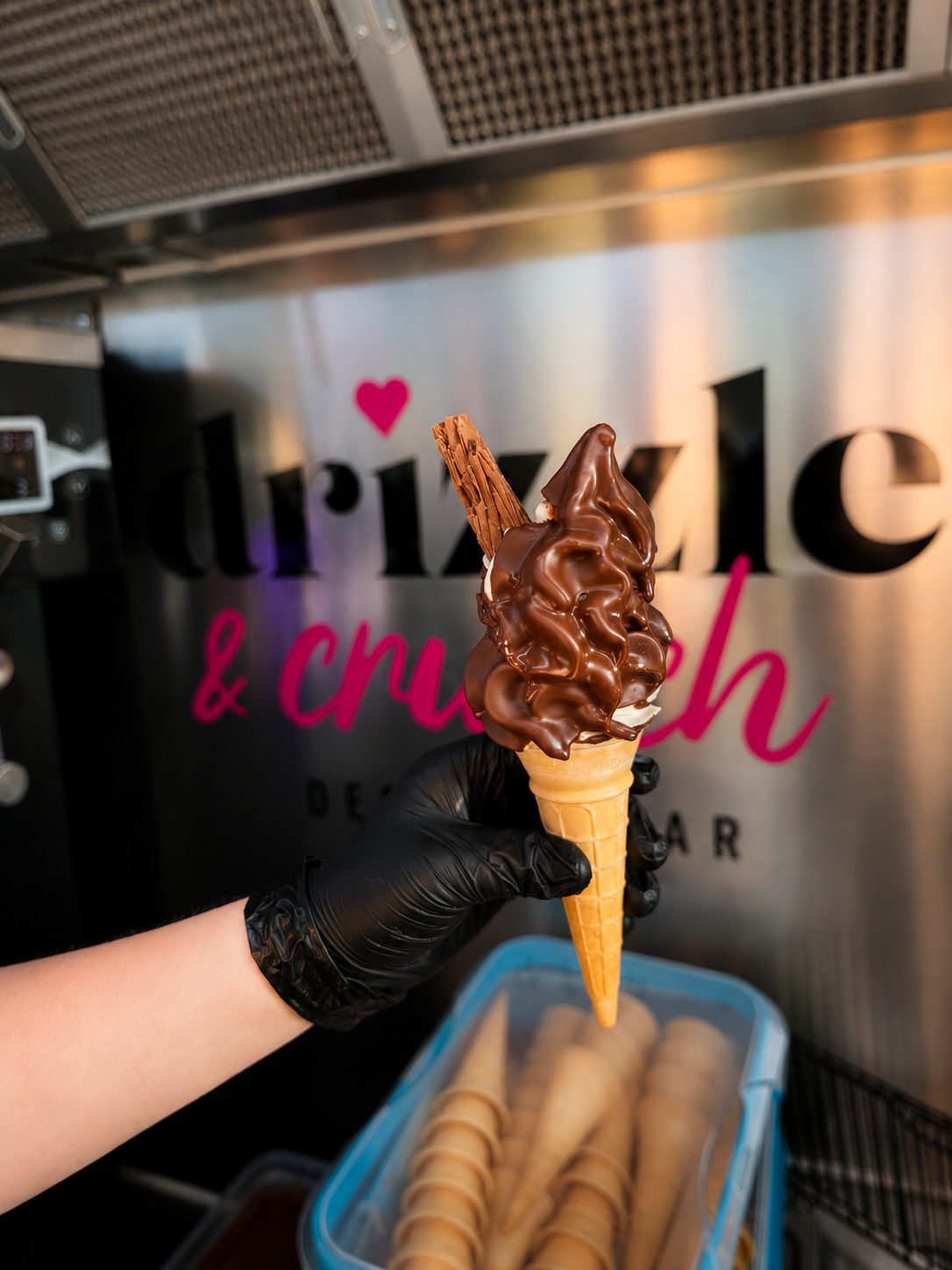 A soft serve cone dipped in chocolate with a Flake, held in a gloved hand